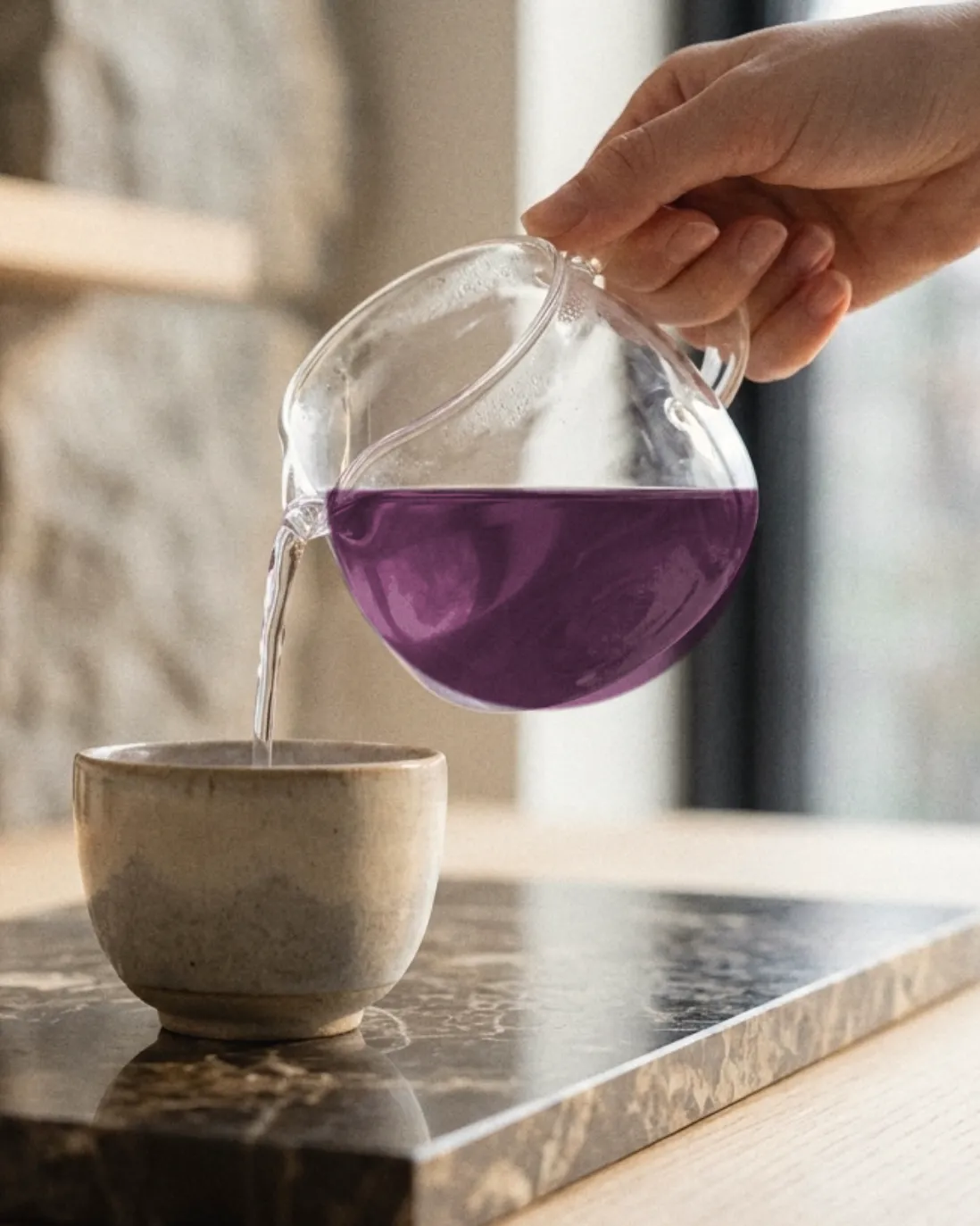 Pouring lilac-plum Deep Hydration from a glass teapot into a ceramic cup